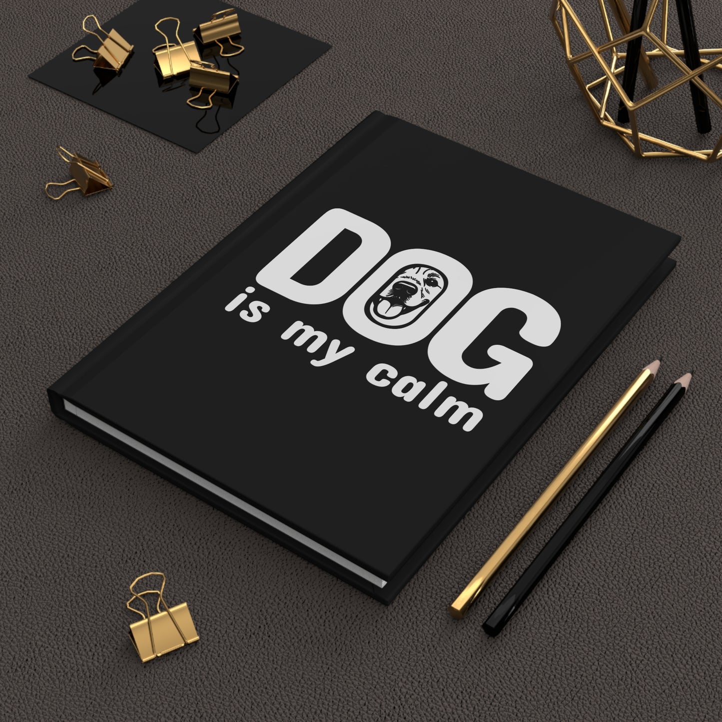 Black notebook with 'DOG is my calm' text on a dark surface with office supplies.