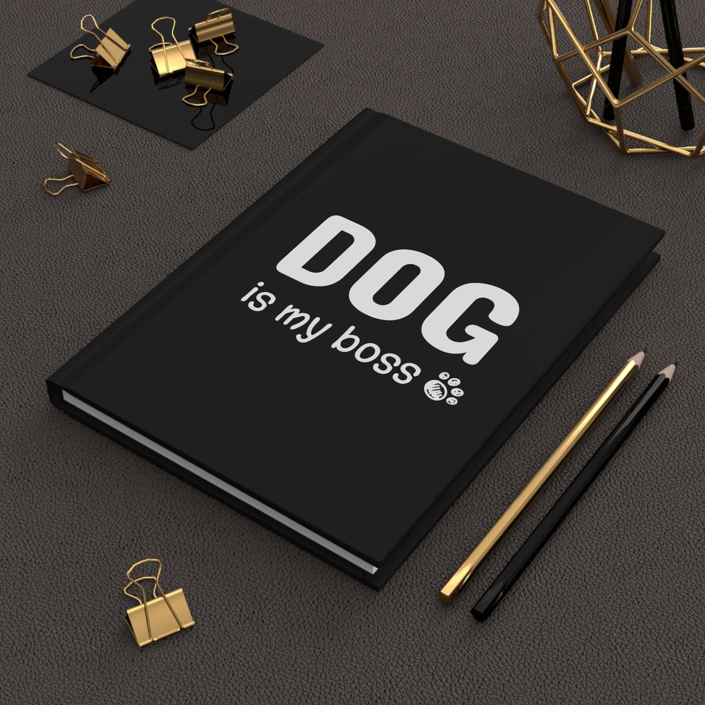 Black notebook with 'DOG is my boss' text on a dark surface with office supplies.