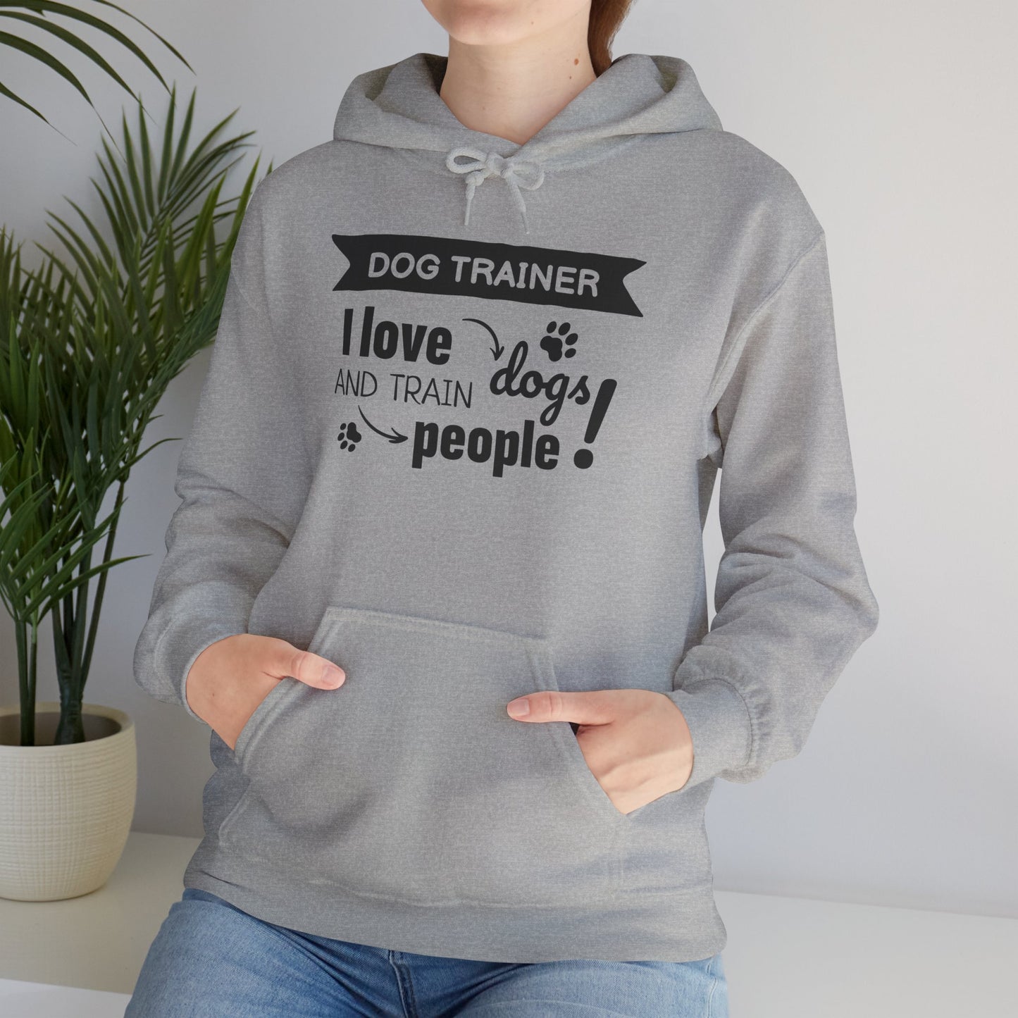 Person wearing a gray hoodie with text 'Dog Trainer: I love dogs and train people' in a home setting.