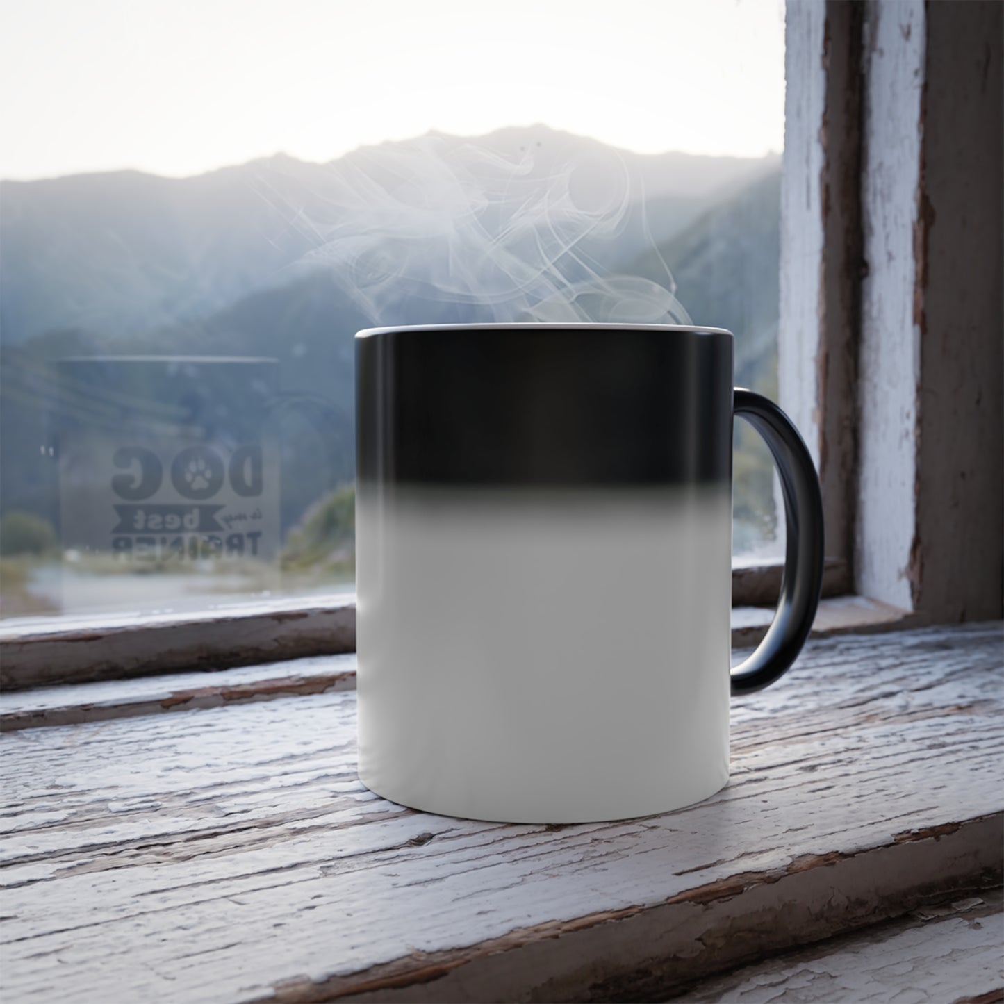 Black and white gradient mug on a wooden surface with a window view of mountains and water.