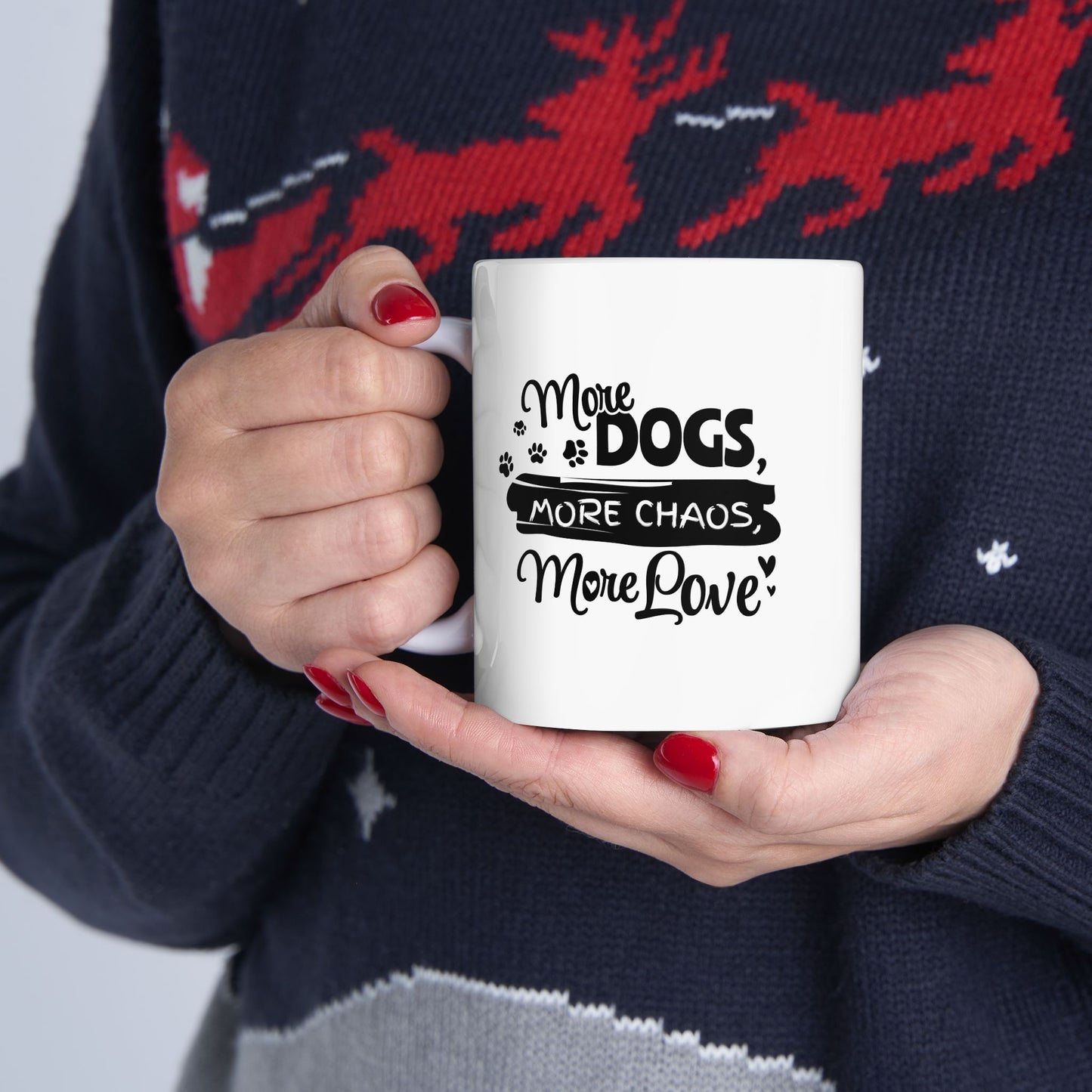 Person holding a mug with 'More Dogs, More Chaos, More Love' text against a dark sweater background.