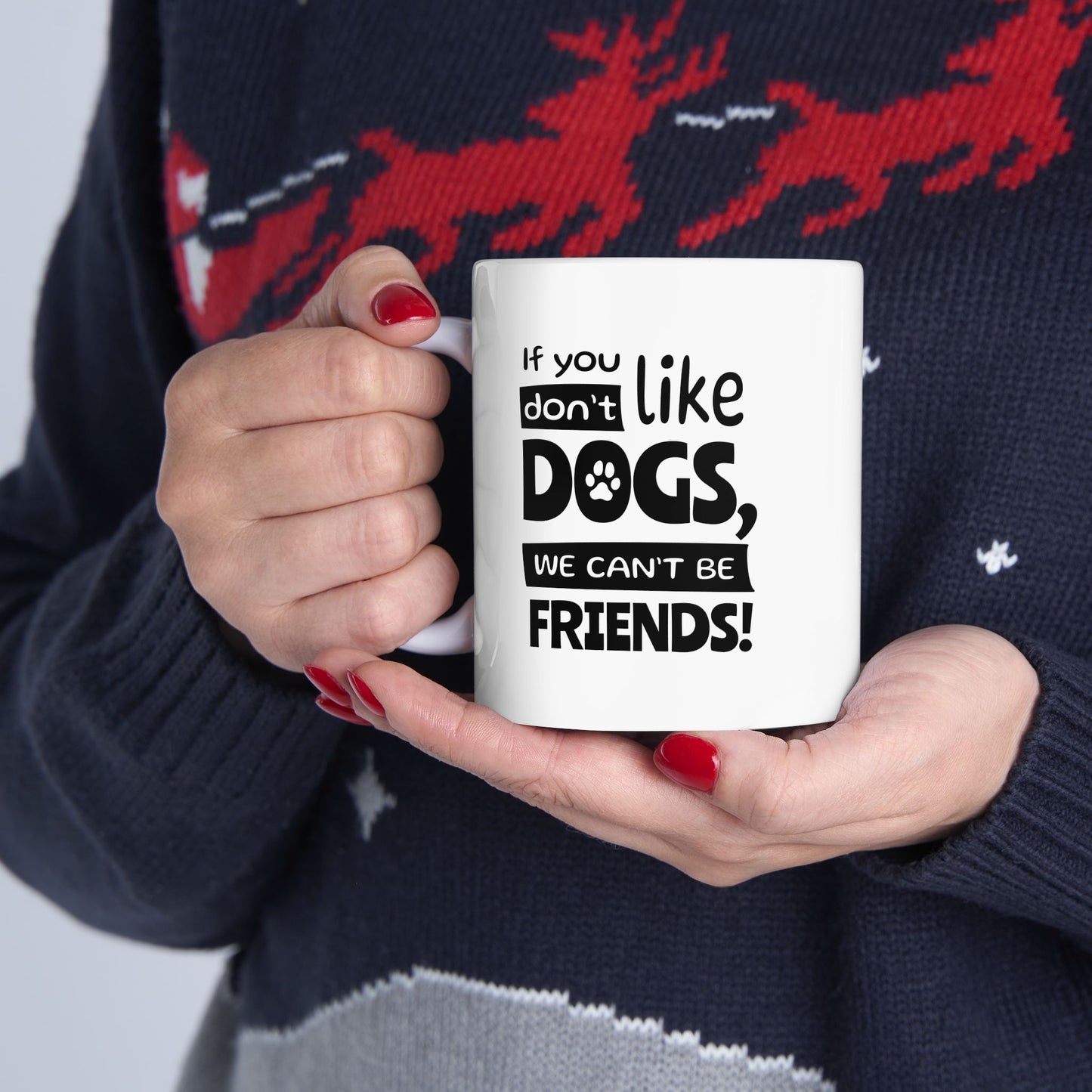 Person holding a mug with text 'If you don't like dogs, we can't be friends!' against a dark sweater background.