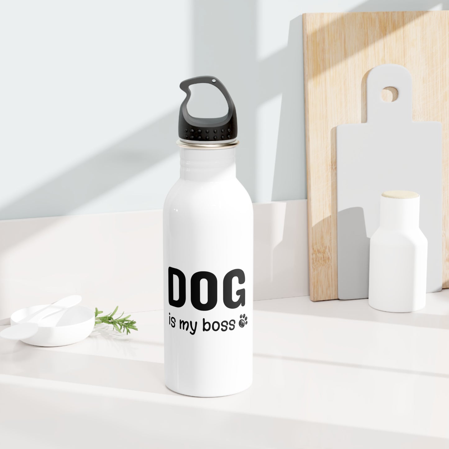 White water bottle with 'DOG is my boss' text on a white surface with wooden cutting boards in the background.