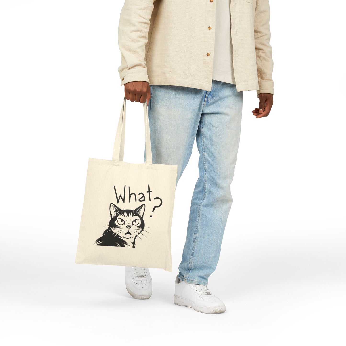 Person holding a tote bag with a cat graphic and 'What?' text on a white background