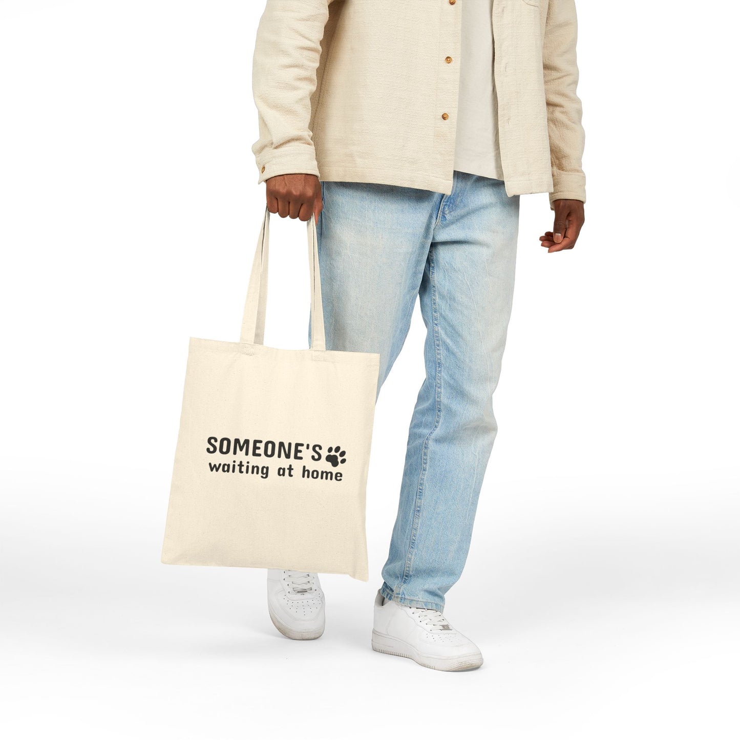 Person holding a tote bag with text on a white background