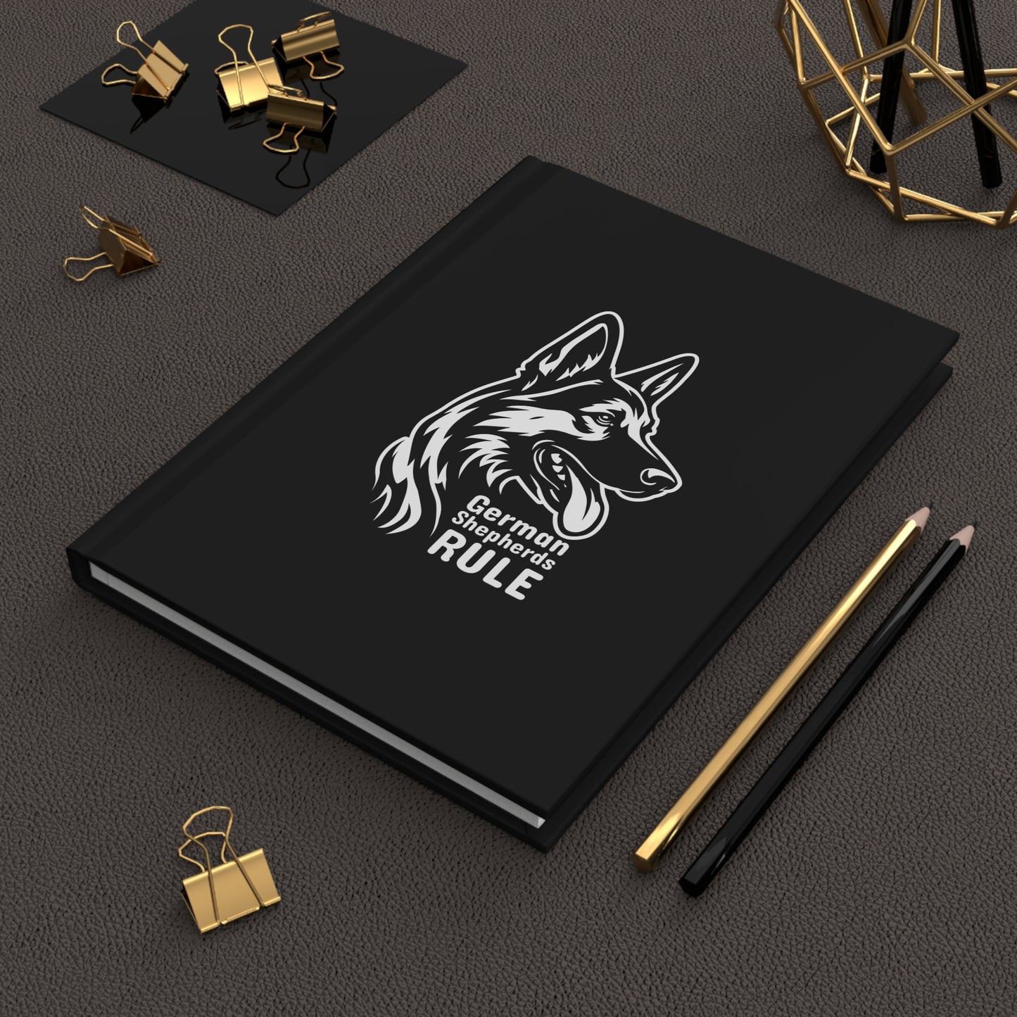 Black notebook with a German Shepherd design and 'German Shepherds Rule' text on a dark surface with office supplies.