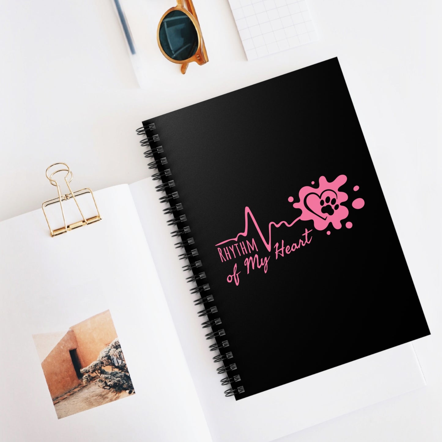 Black notebook with pink design and text on a white surface