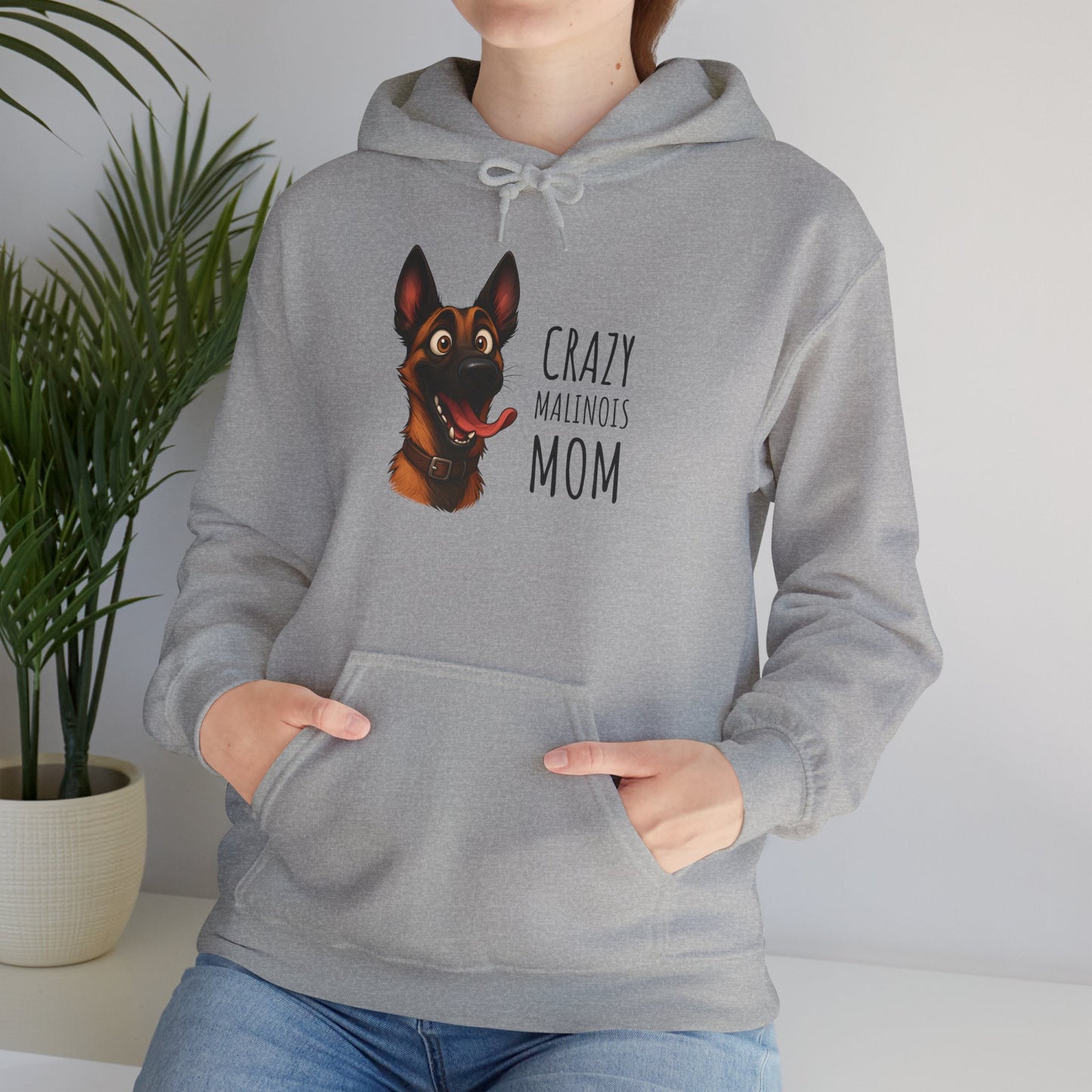 Person wearing a gray hoodie with a dog graphic and text, standing indoors with a plant in the background.