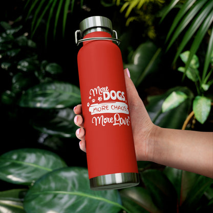 Red water bottle with white text held by a hand against a green leafy background