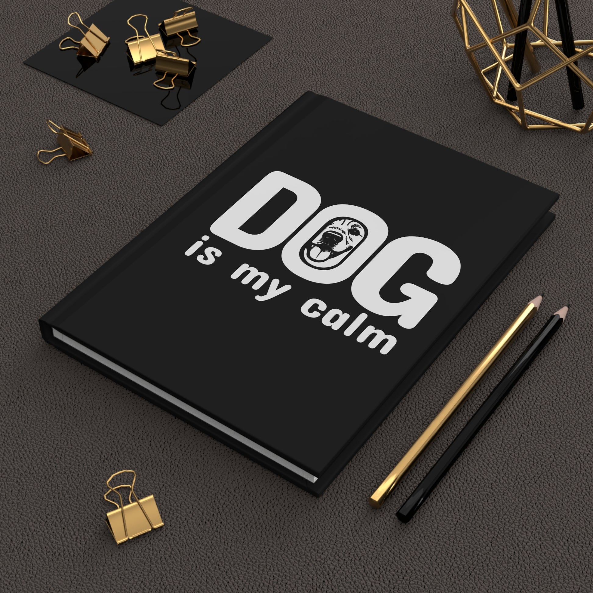 Black notebook with 'DOG is my calm' text on a dark surface with office supplies.