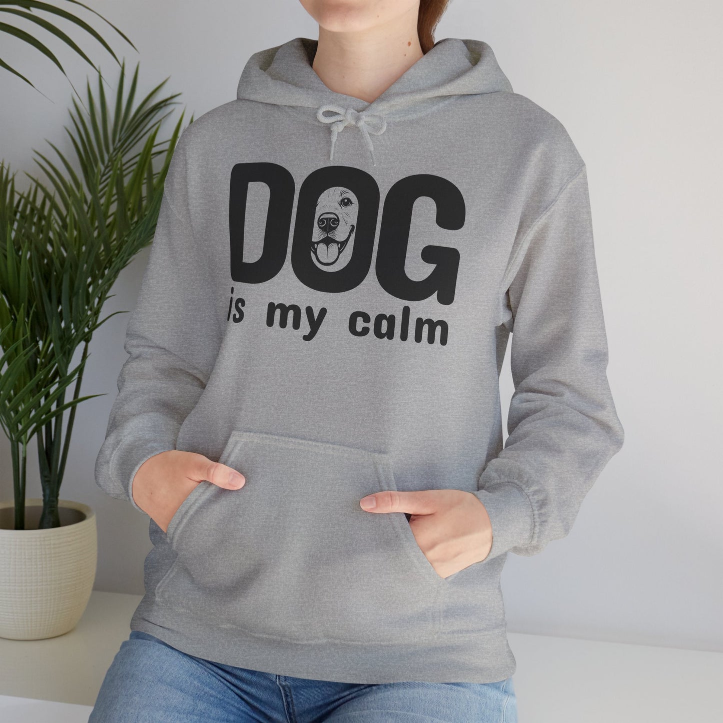 Person wearing a gray hoodie with 'DOG is my calm' text, standing indoors with a plant in the background.