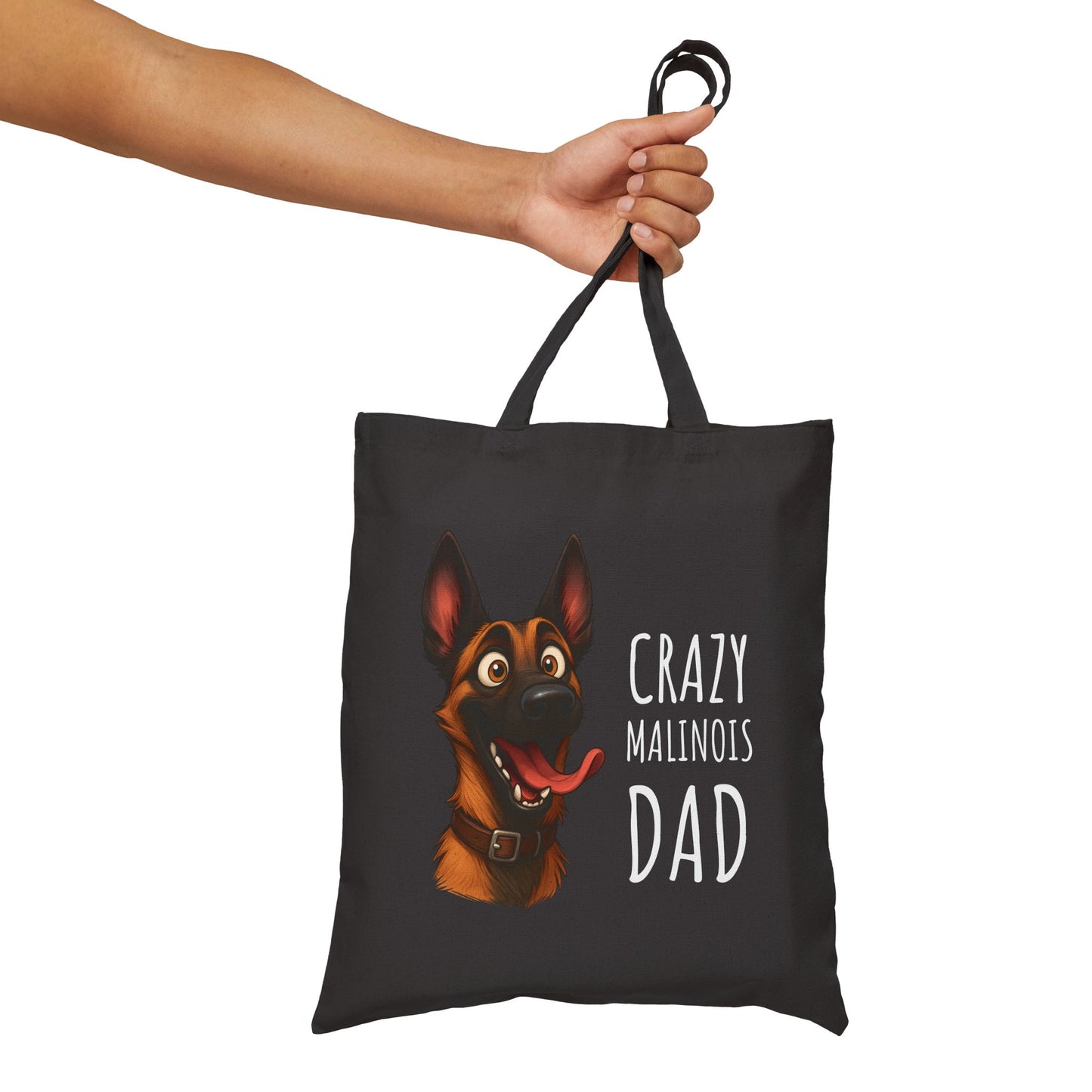 Black tote bag with a dog illustration and text held by a hand on a white background