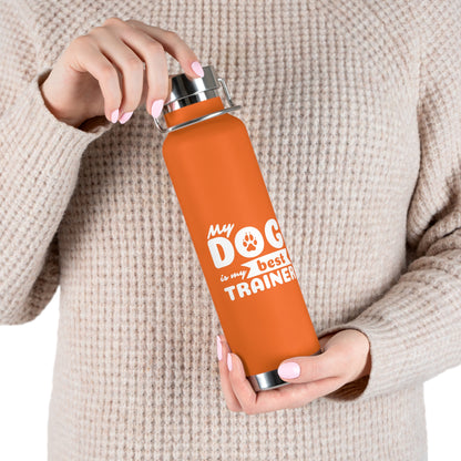 Person holding an orange water bottle with 'My dog is my trainer' text