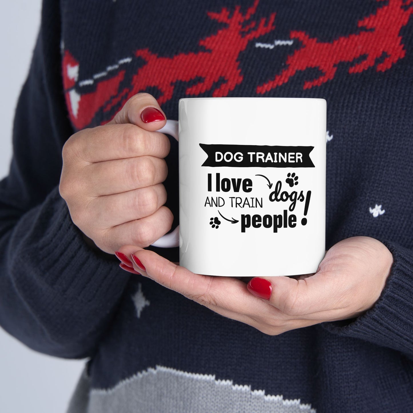 Person holding a mug with a dog trainer design, wearing a festive sweater.