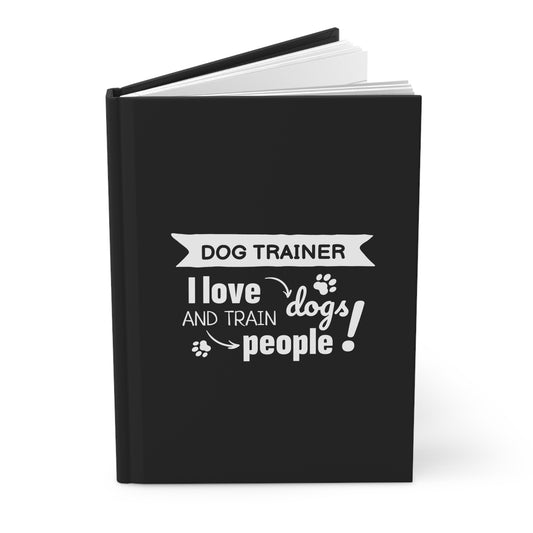 Black notebook with white text 'Dog Trainer I love dogs and train people!' on a white background