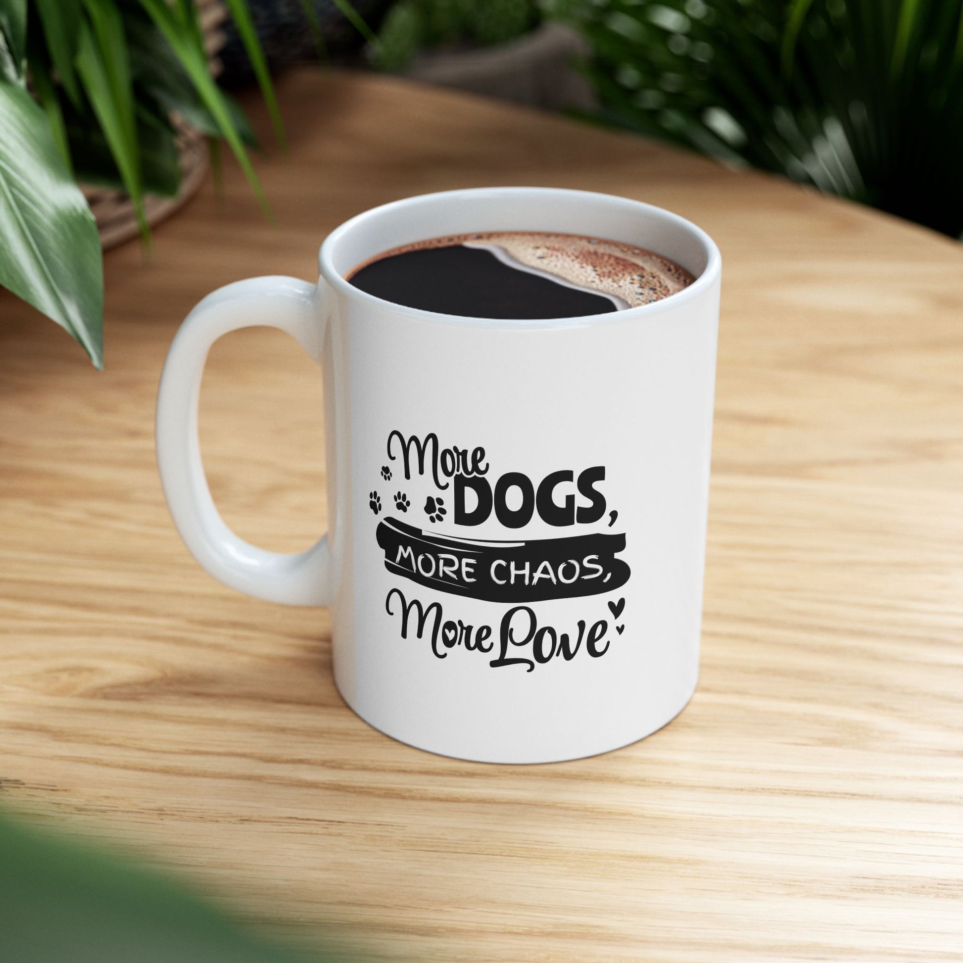 White mug with text 'More Dogs, More Chaos, More Love' on a wooden table.