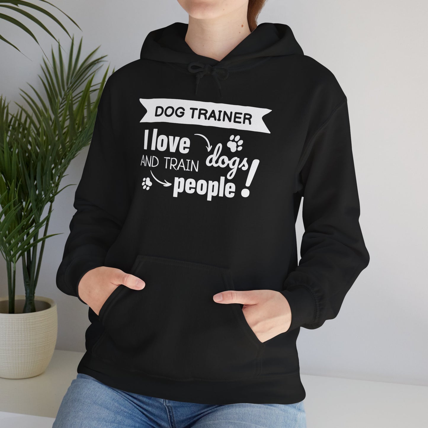 Person wearing a black hoodie with text 'Dog Trainer I love dogs and train people' in a home setting.