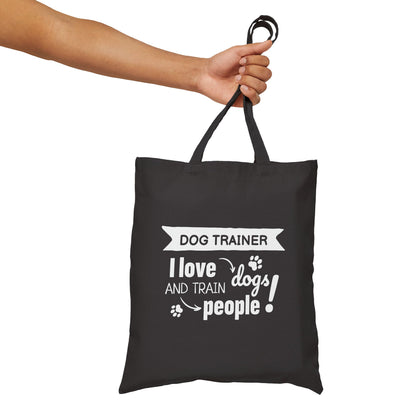 Black tote bag with white text held by a hand on a white background