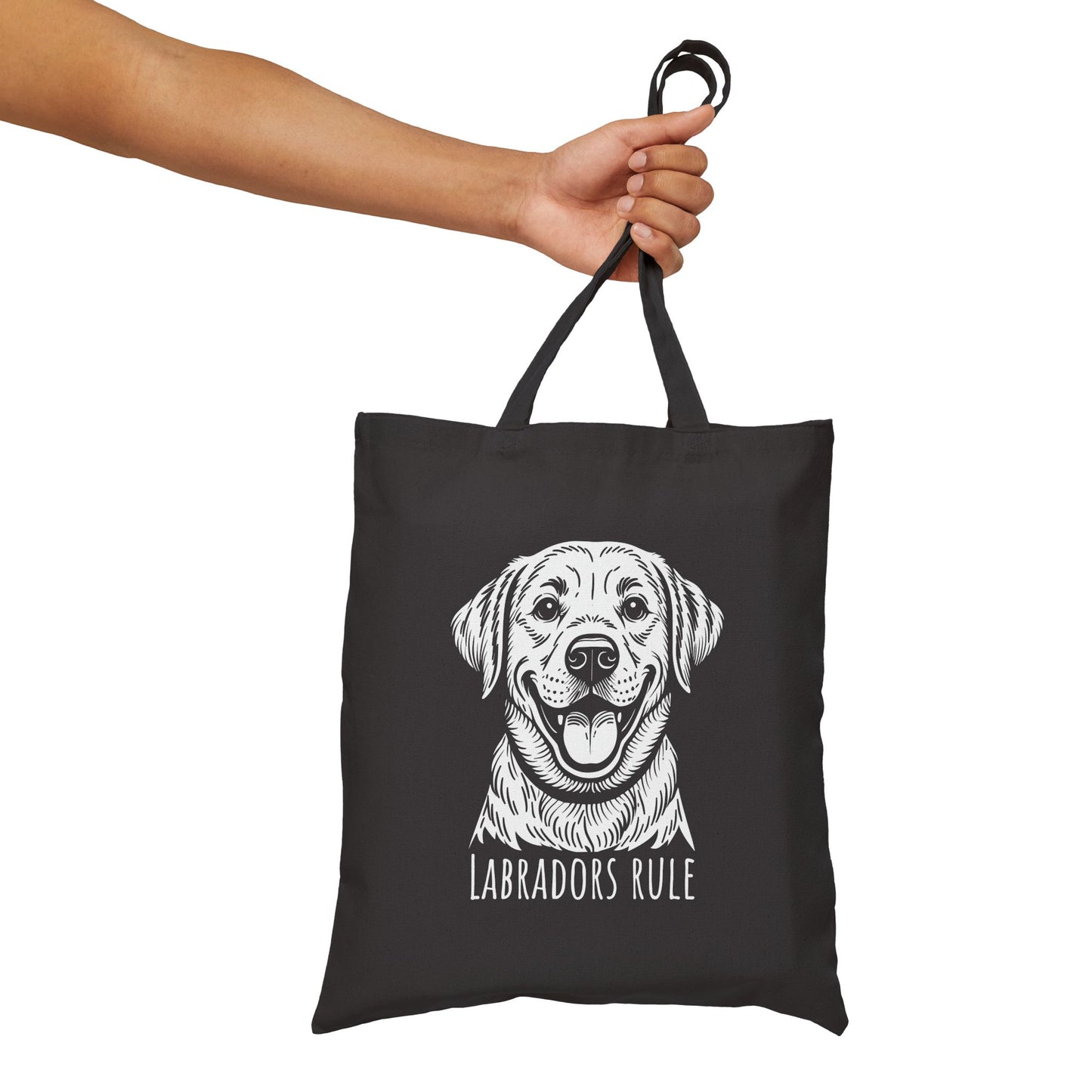 Black tote bag with a white dog illustration and 'Labradors Rule' text, held by a hand against a white background.