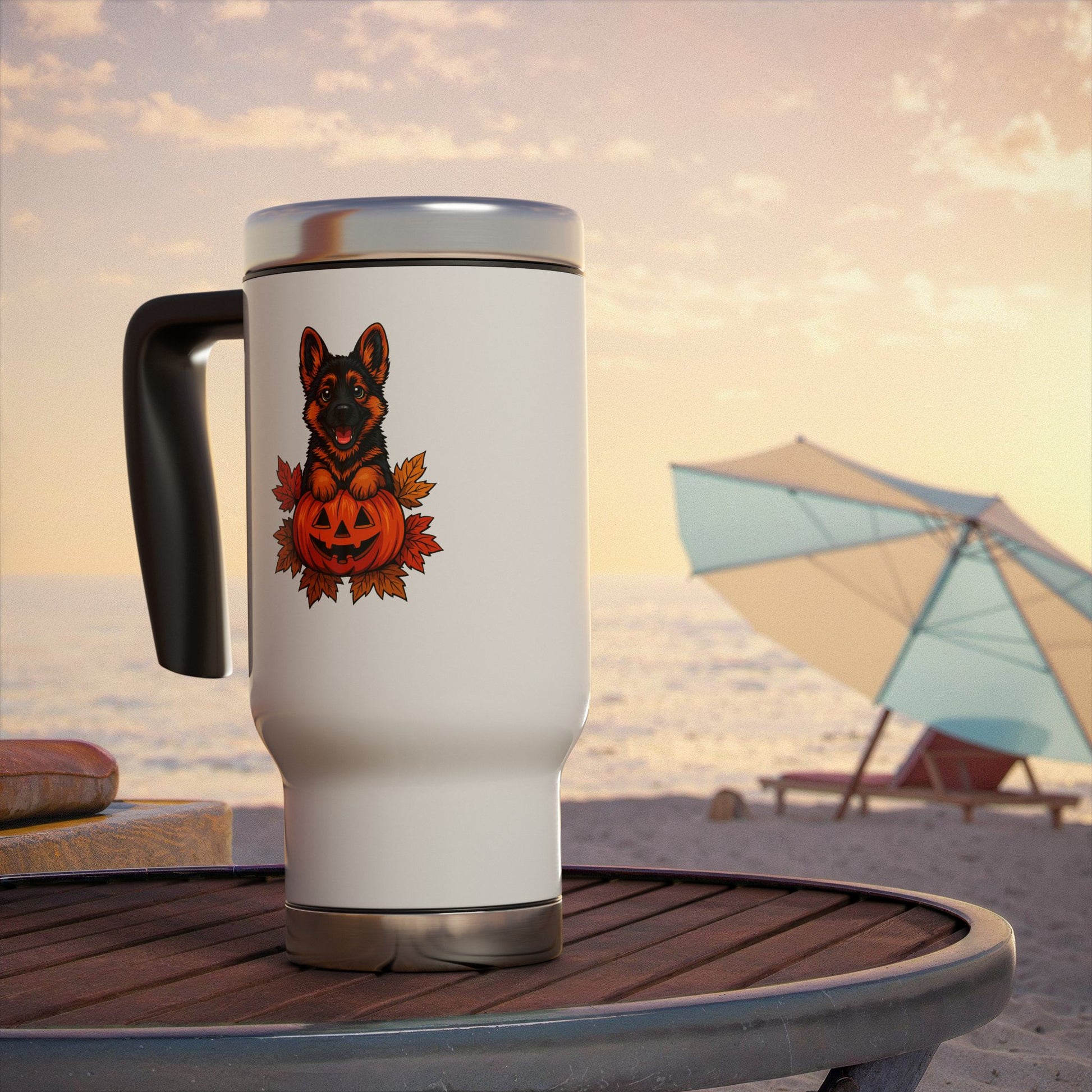 White travel mug with a dog and pumpkin design on a beach table with an umbrella in the background.