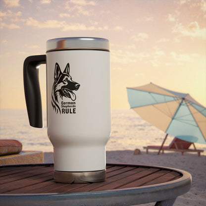 White travel mug with black handle featuring a German Shepherd design on a beach table with a sunset background.
