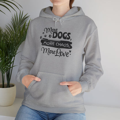 Person wearing a gray hoodie with text 'More Dogs, More Chaos, More Love' in a home setting.