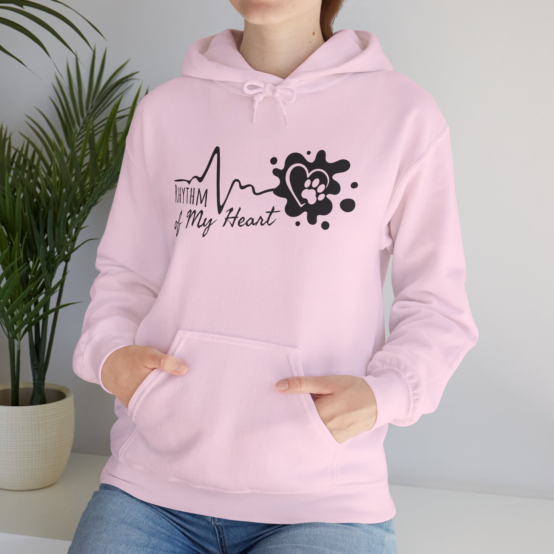 Person wearing a pink hoodie with a heart-themed design against a neutral background