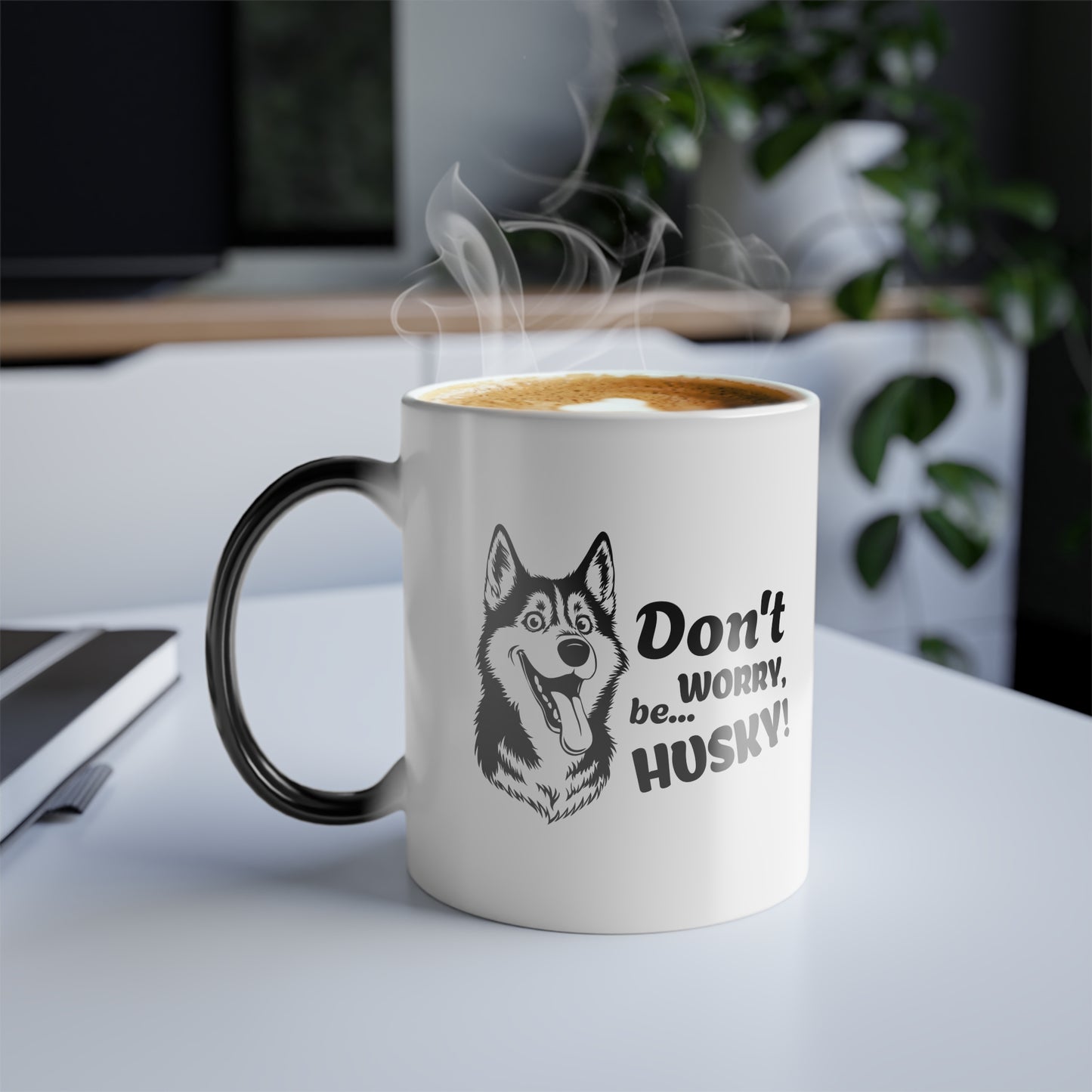 White mug with black handle and husky design, filled with steaming coffee on a desk.