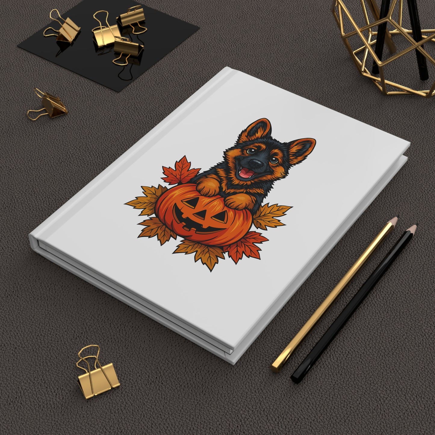 Notebook with a Halloween-themed design featuring a dog and pumpkin on a dark surface with stationery items.