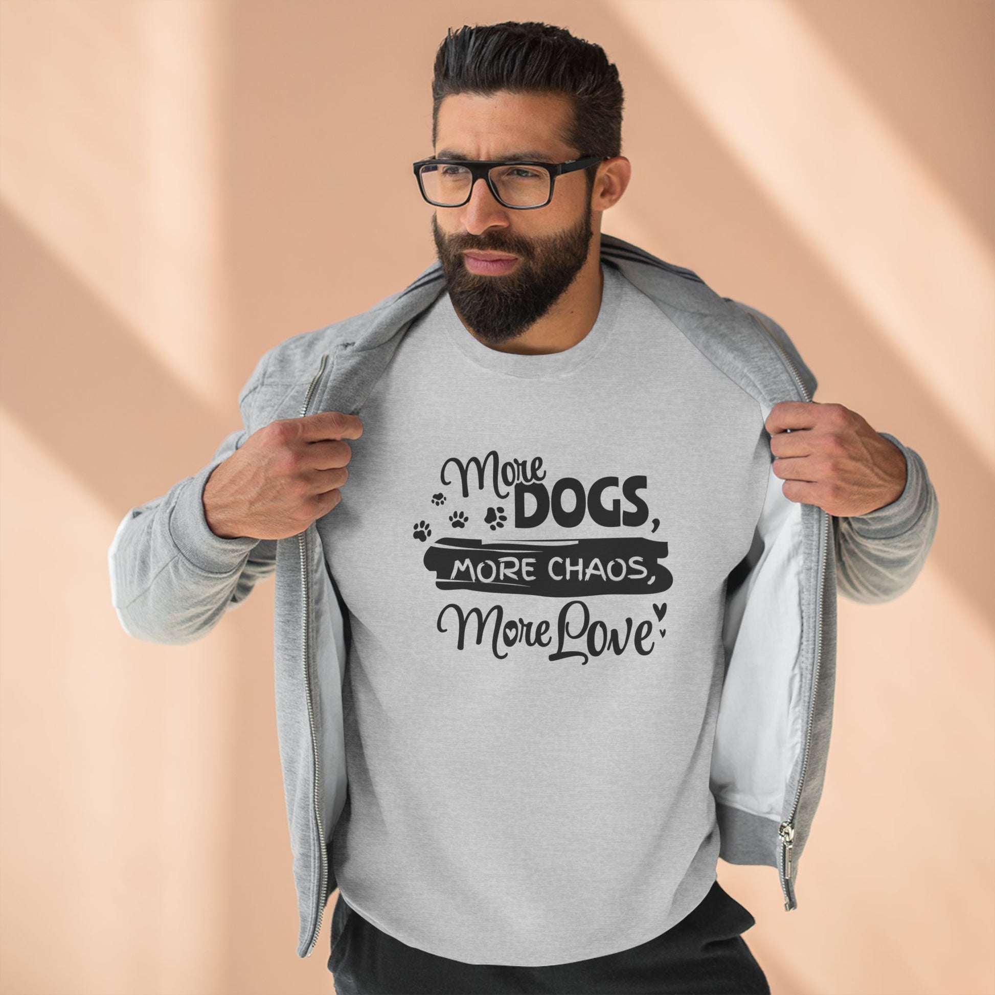 Man wearing a gray sweatshirt with text 'More Dogs, More Chaos, More Love' on a beige background