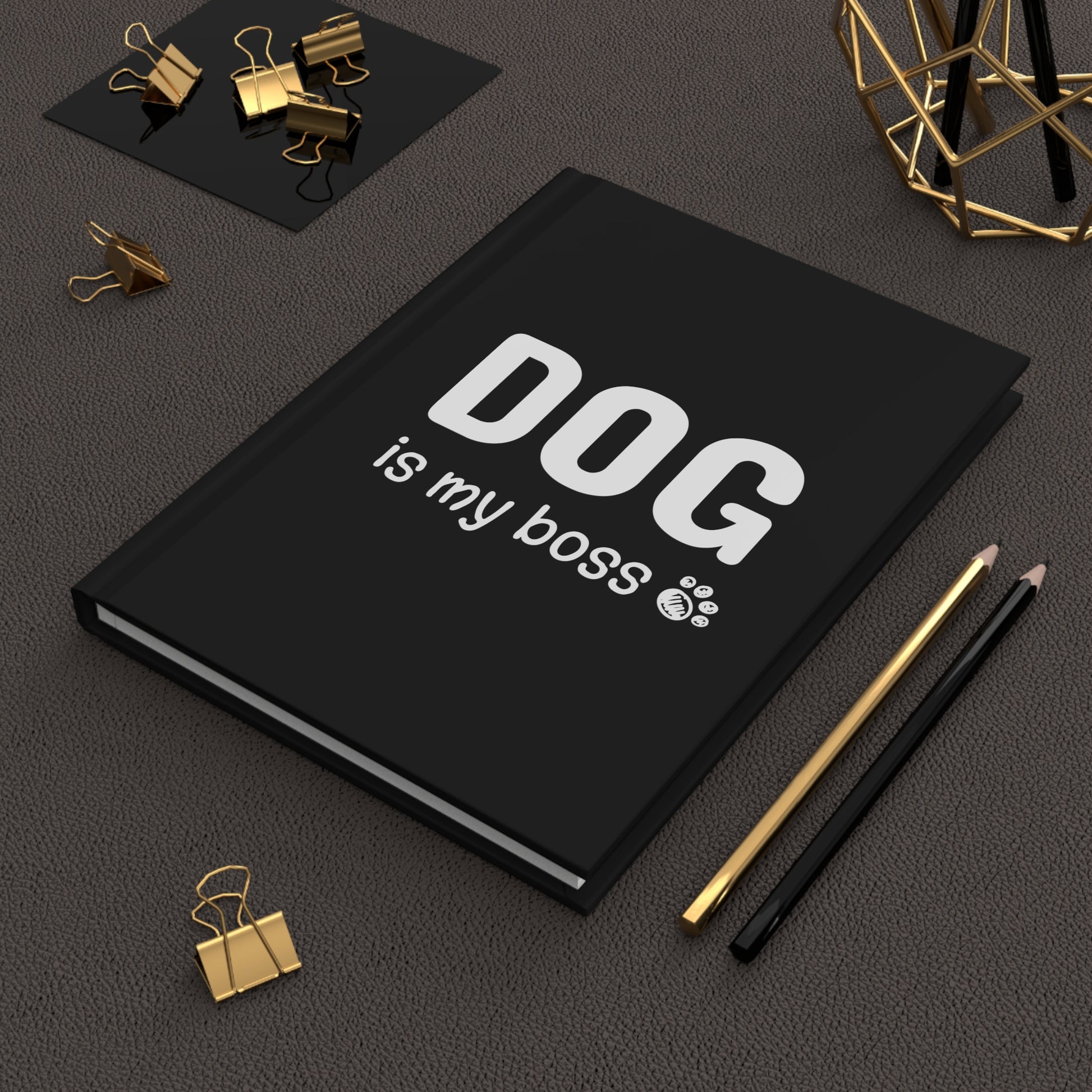 Black notebook with 'DOG is my boss' text on a dark surface with office supplies.