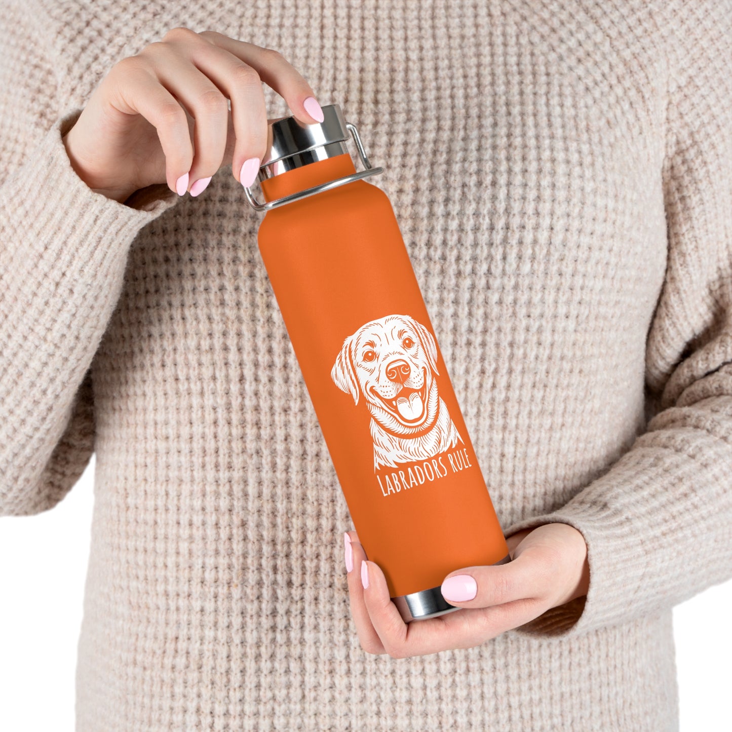 Person holding an orange water bottle with a dog illustration and text on a beige background