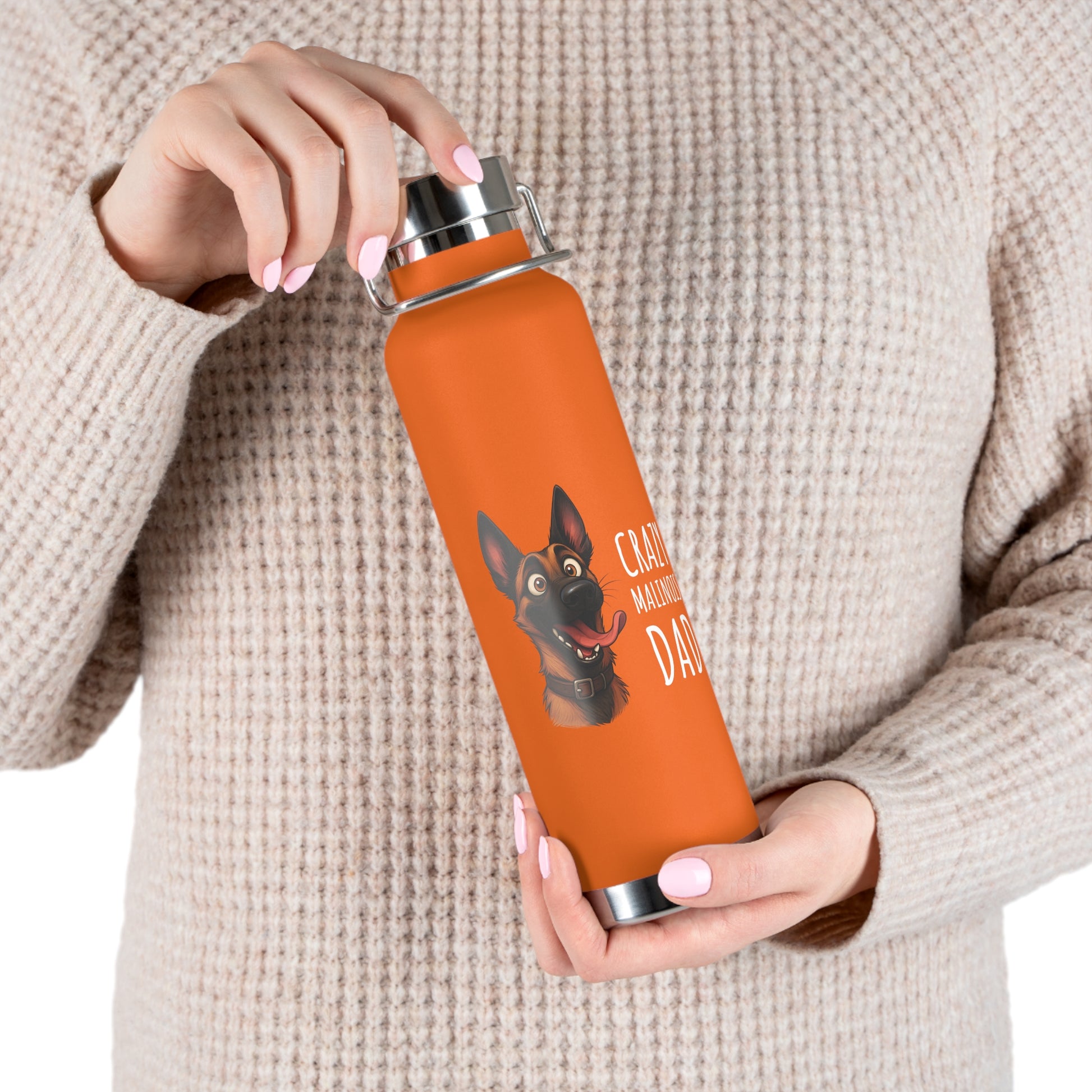 Person holding an orange water bottle with a dog illustration and text.