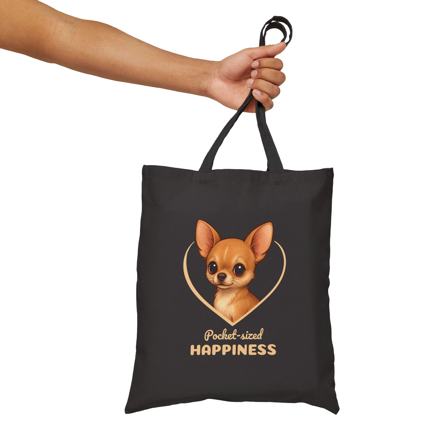 Black tote bag with a dog illustration and 'Pocket-sized Happiness' text, held by a hand.