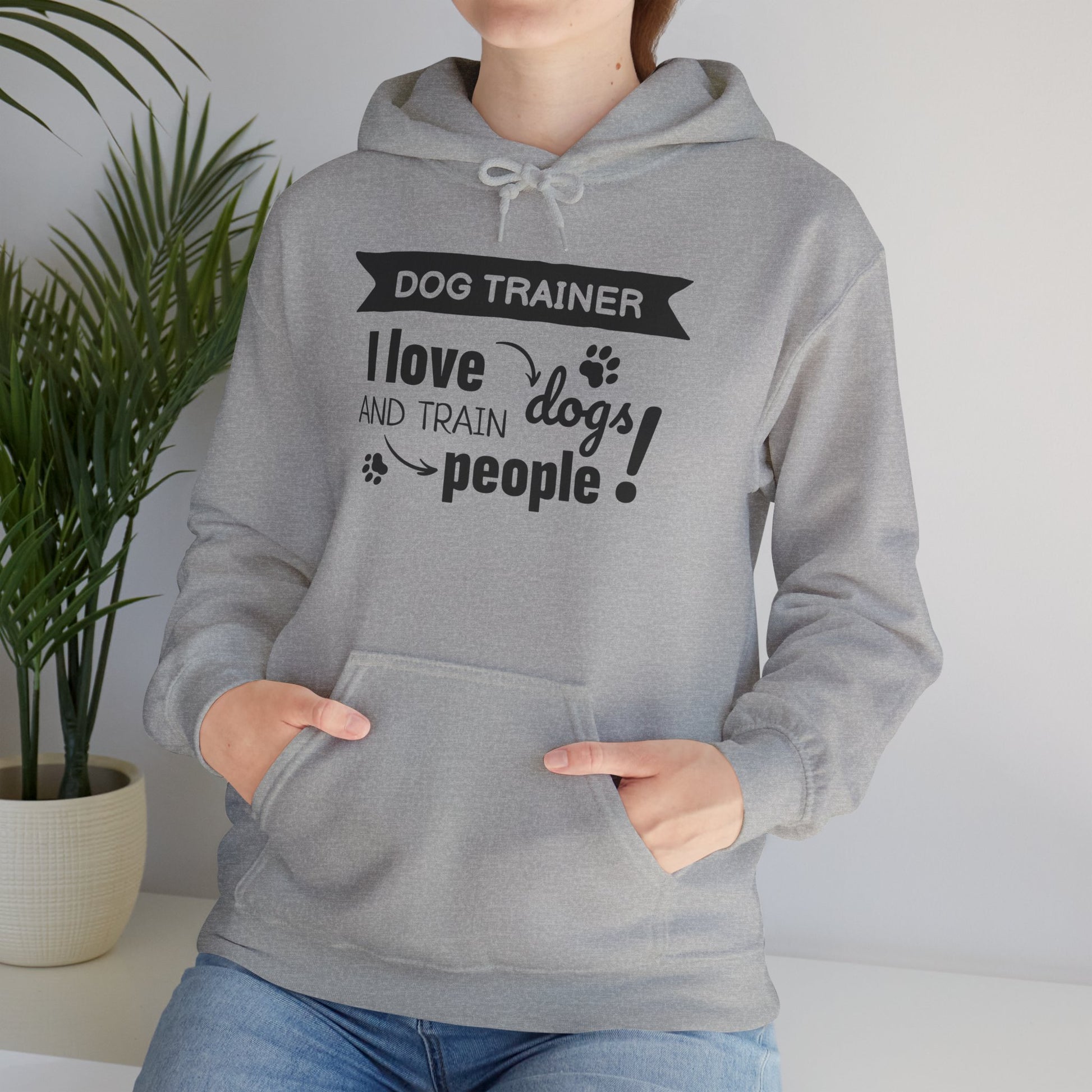 Person wearing a gray hoodie with text 'Dog Trainer: I love dogs and train people' in a home setting.