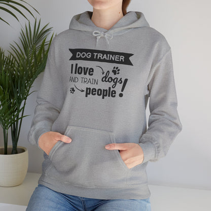 Person wearing a gray hoodie with text 'Dog Trainer: I love dogs and train people' in a home setting.