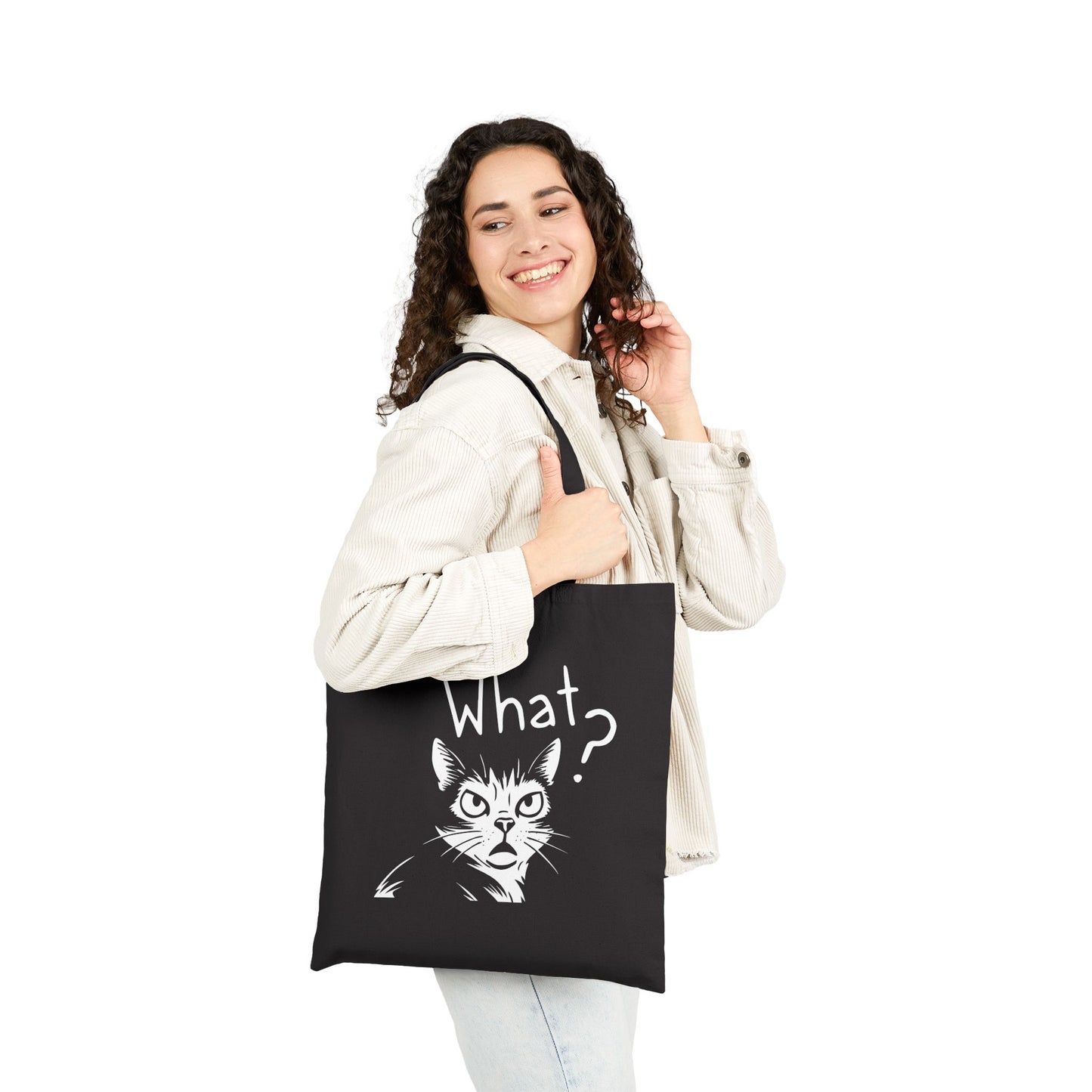 Woman holding a black tote bag with a cat graphic and text.