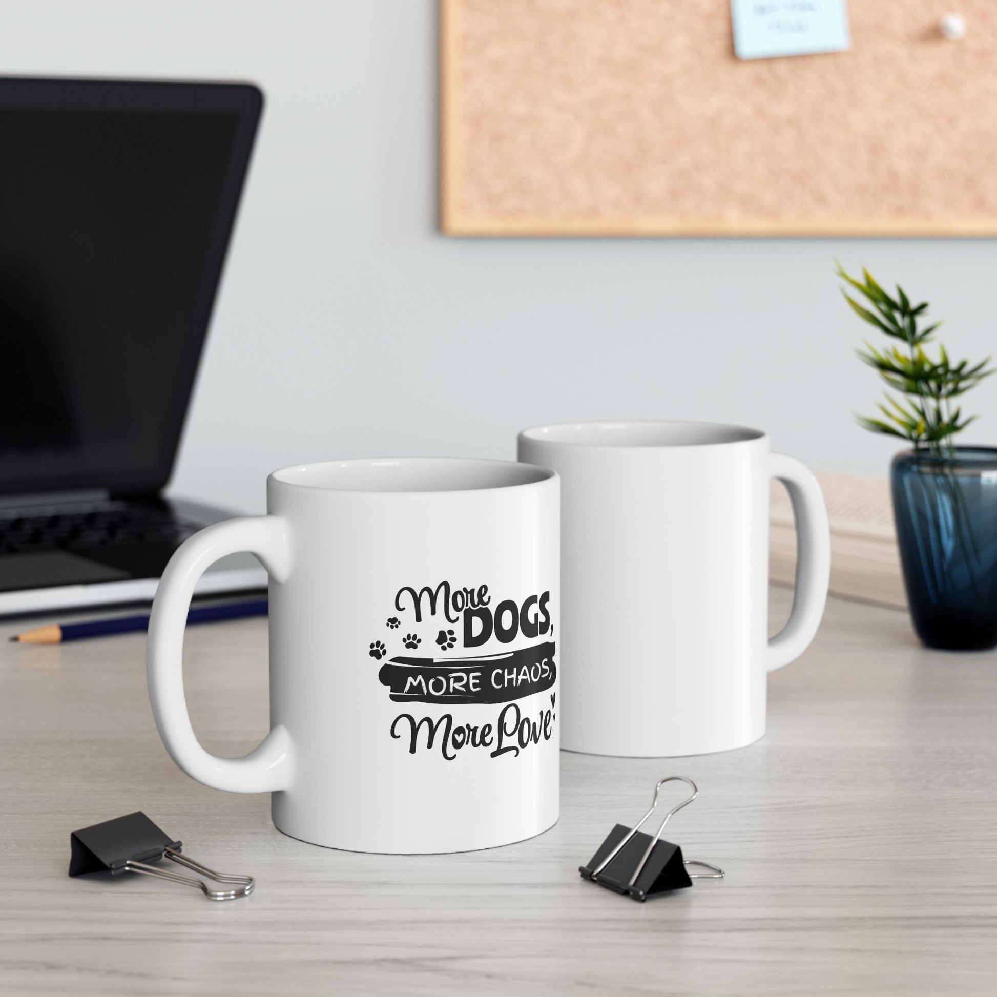 Two white mugs on a desk with one featuring text about dogs and life.