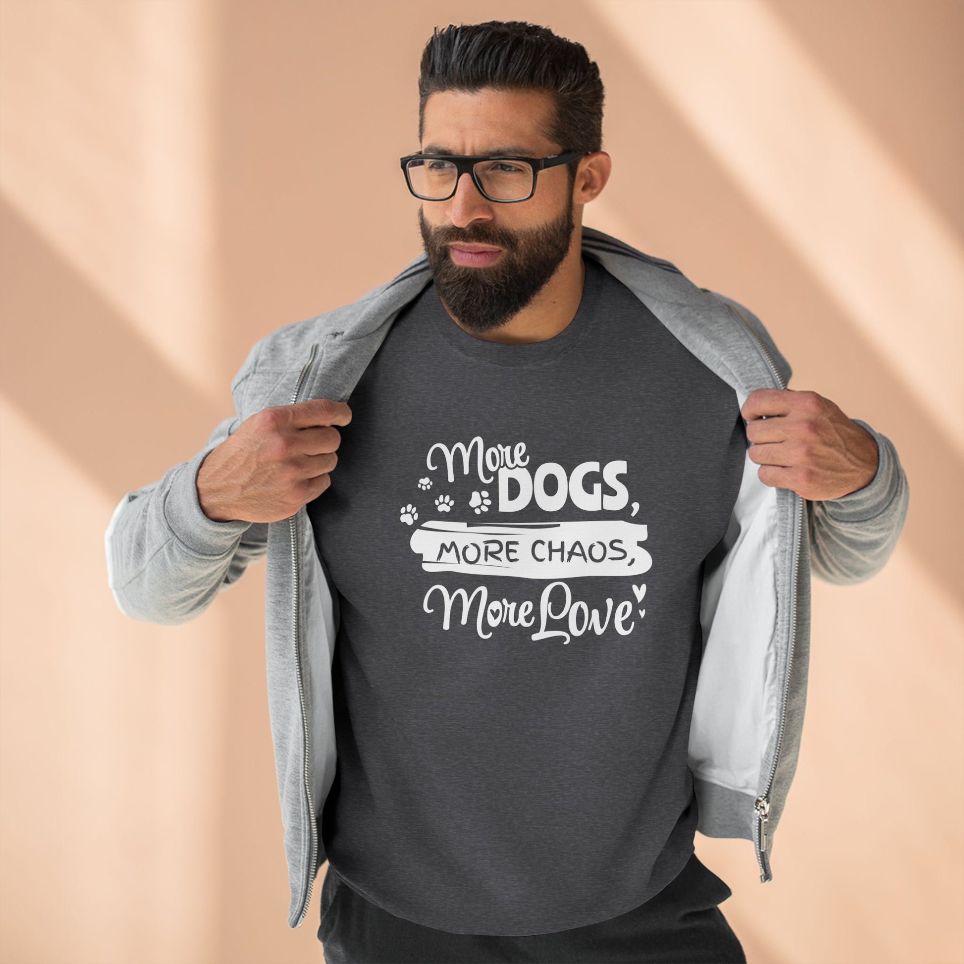 Man wearing a dark gray t-shirt with 'More Dogs, More Chaos, More Love' text on a beige background