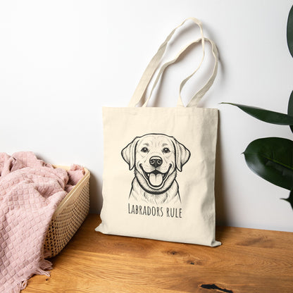 Beige tote bag with a dog illustration and 'Labradors Rule' text on a wooden surface.
