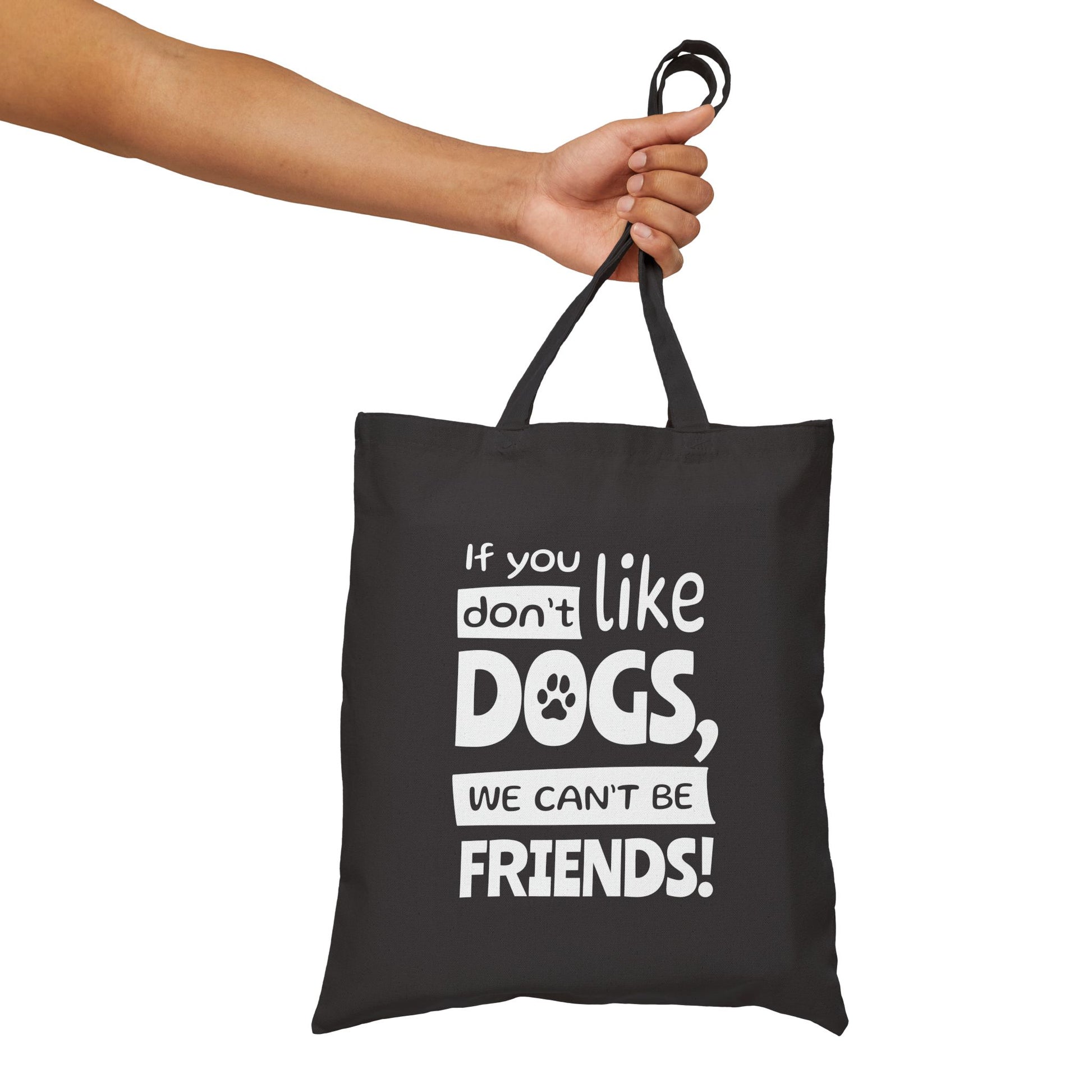 Black tote bag with white text held by a hand on a white background
