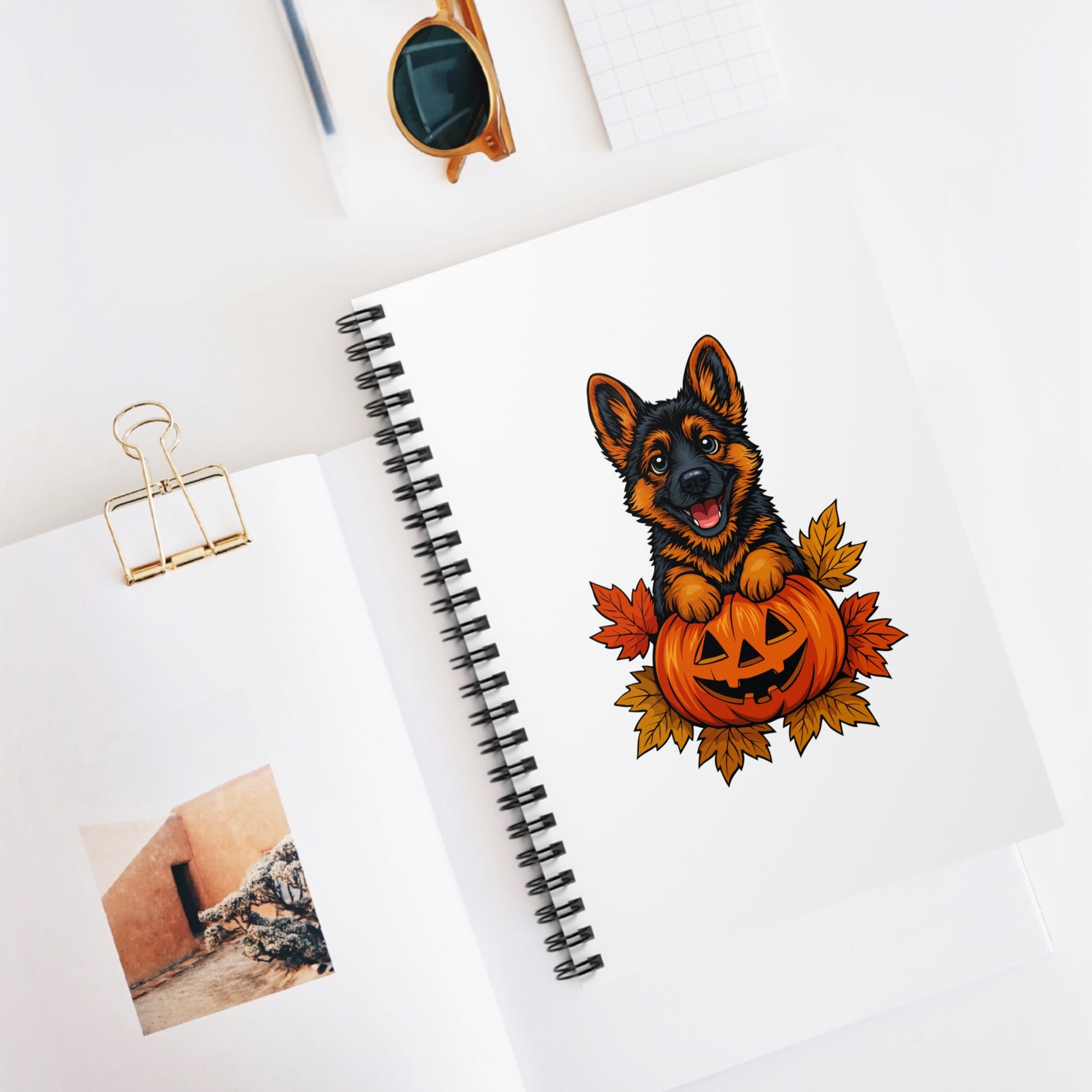 Notebook with a Halloween-themed illustration of a dog with a pumpkin on a white surface.