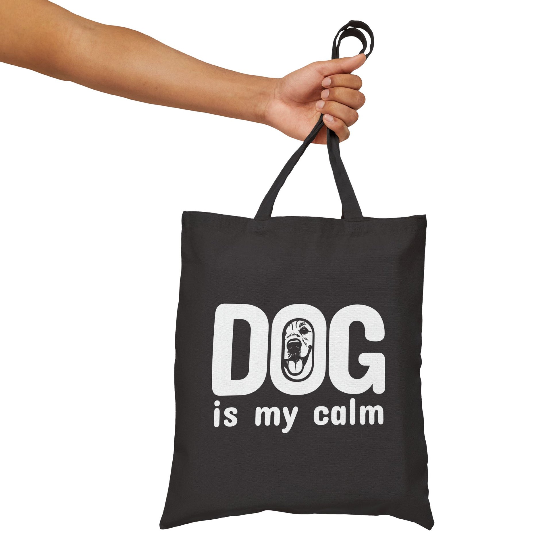 Black tote bag with 'DOG is my calm' text held by a hand on a white background