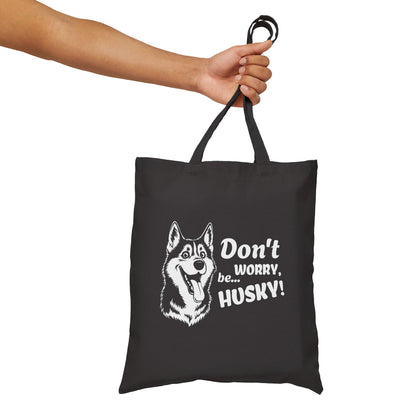 Black tote bag with husky design and text held by a hand on a white background