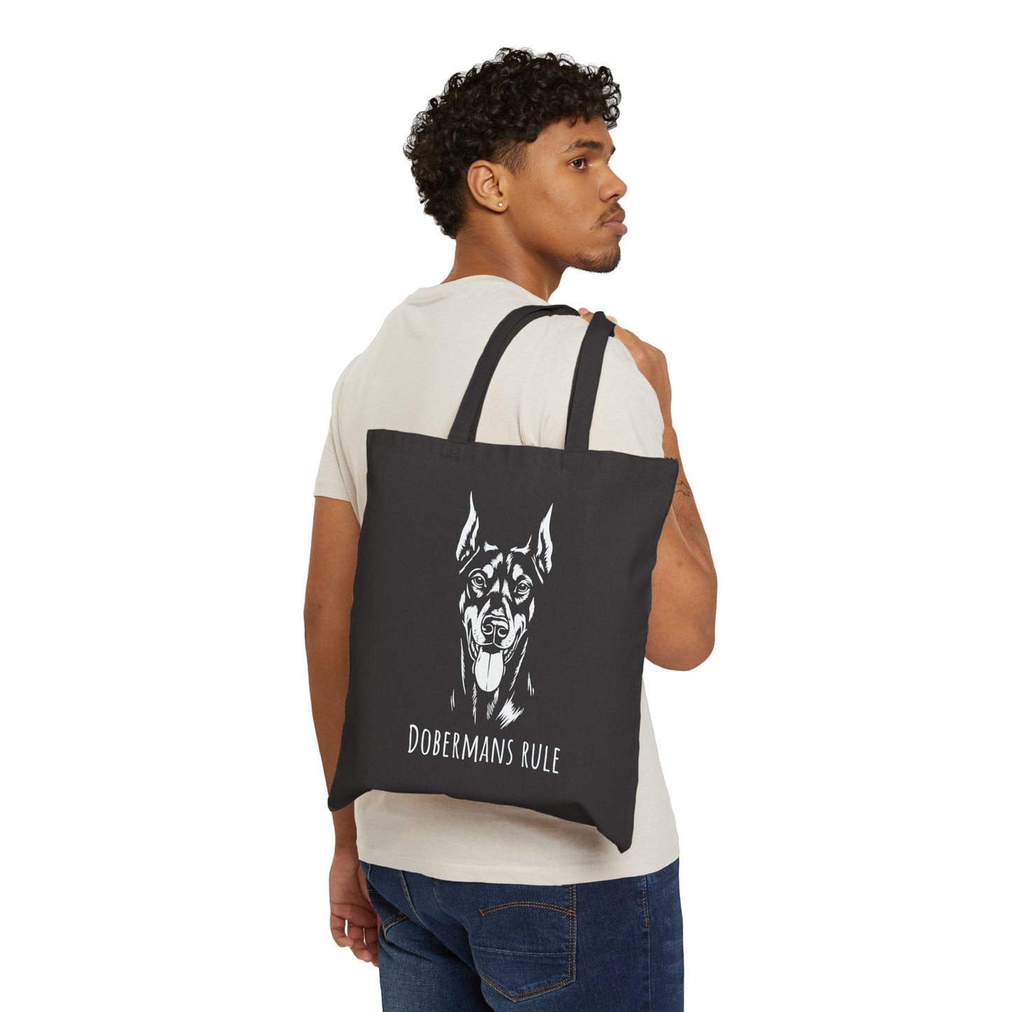 Man carrying a black tote bag with a dog illustration and 'Dobermans Rule' text on a white background