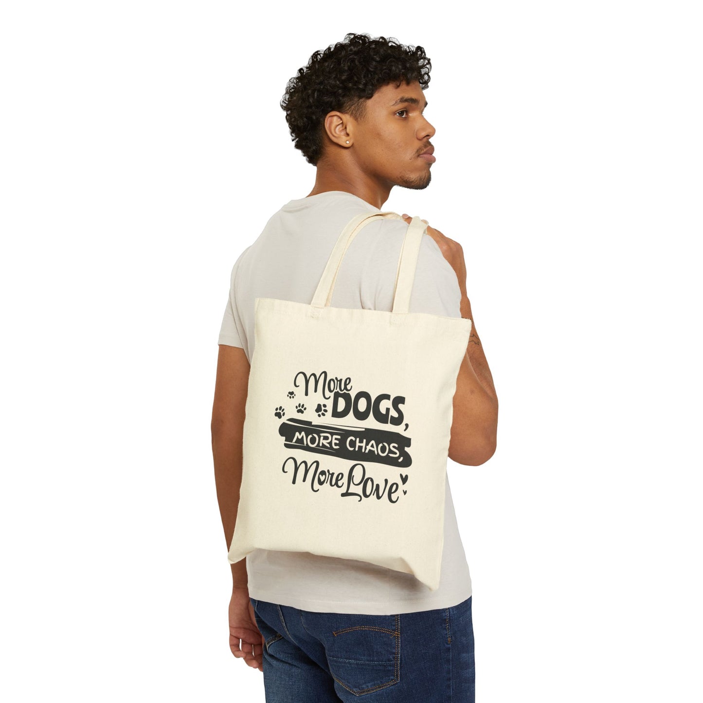 Man carrying a tote bag with text 'More Dogs, More Chaos, More Love' on a white background