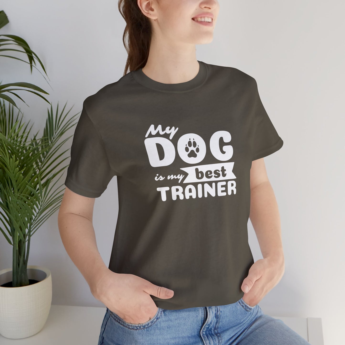 Person wearing a dark gray t-shirt with 'My dog is my best trainer' text, standing indoors.