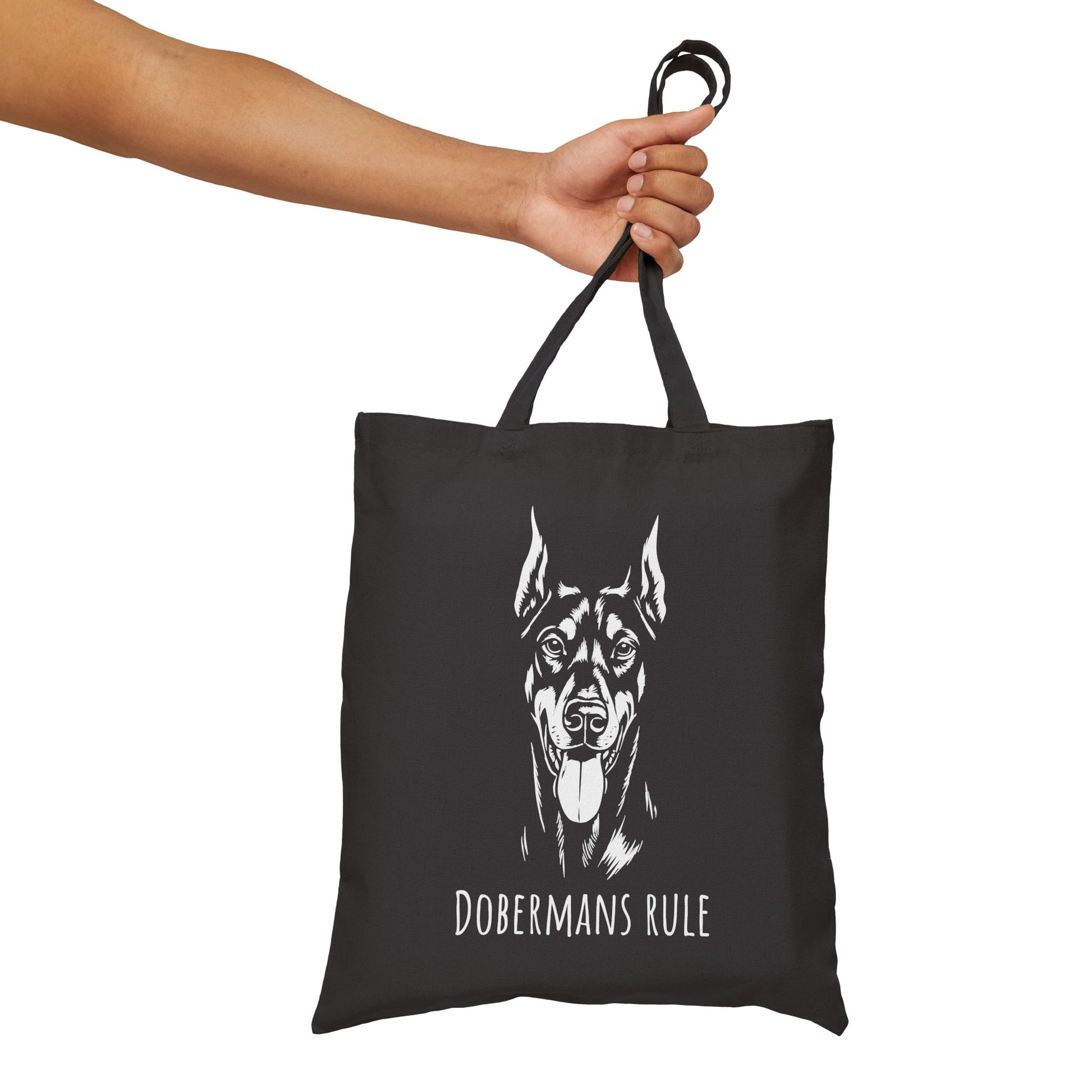 Black tote bag with a Doberman design and 'Dobermans Rule' text, held by a hand against a white background.