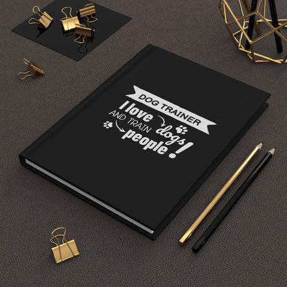 Black notebook with a white text design on a dark surface with office supplies.