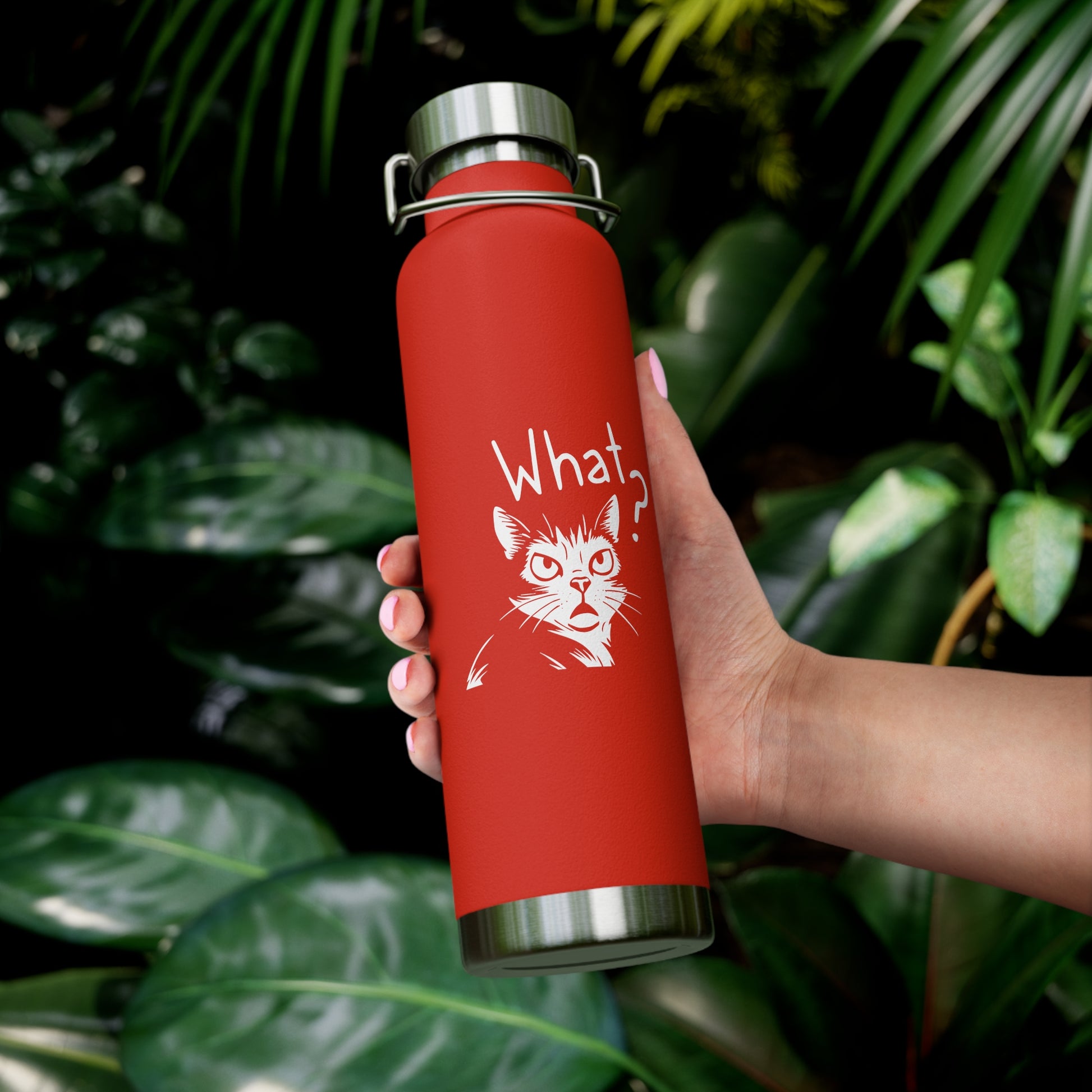 Red water bottle with a cat illustration and text held by a hand against a leafy background